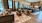 a clubroom with a couch, chairs, tables and a rug