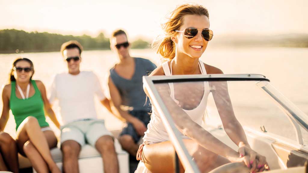 Women driving boat on water with friends